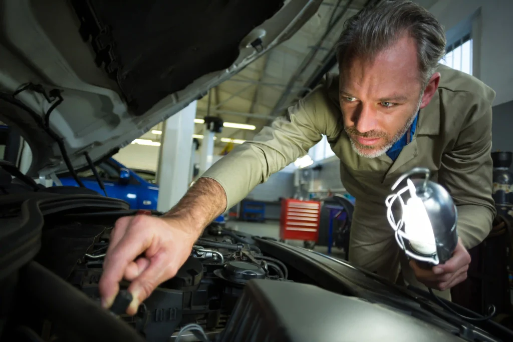 mechanic examining car with lamp Paint And Body
