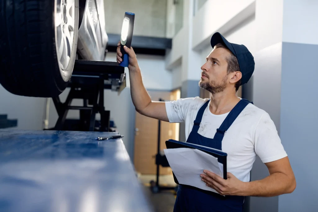 mid adult mechanic using flashlight while examining car auto repair Paint And Body